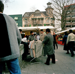 846389 Afbeelding van een groepje buitenlandse mannen (gastarbeiders?) bij een kraam met kleding op de markt op het ...
